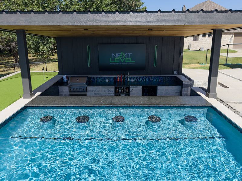 Swim up bar with submerged stools under a pavilion